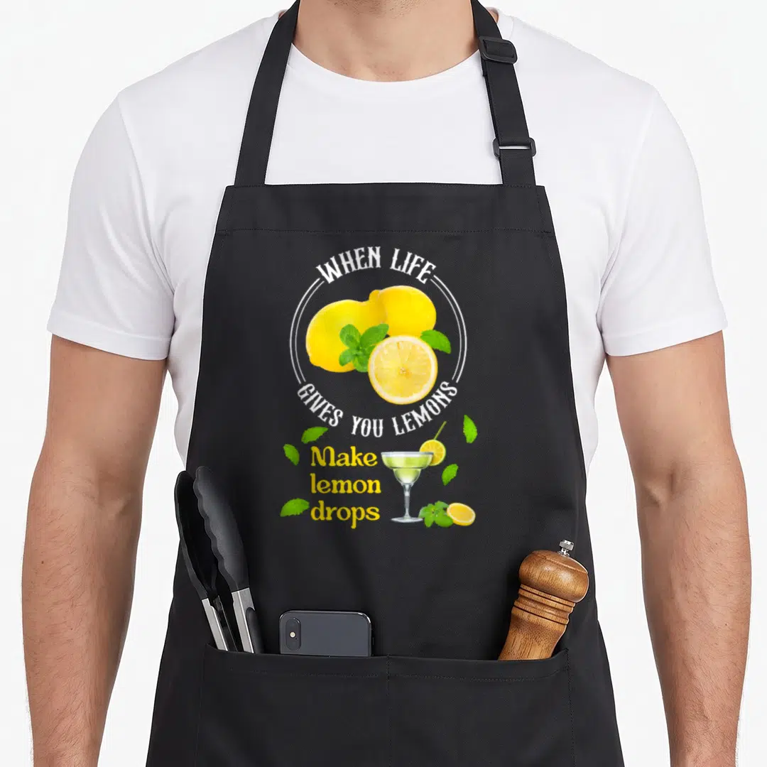 Give for love and lemons apron - Yellow lemons, green mint, cocktail glass, and white arched text on black fabric — shown on a black cotton canvas apron against a white background