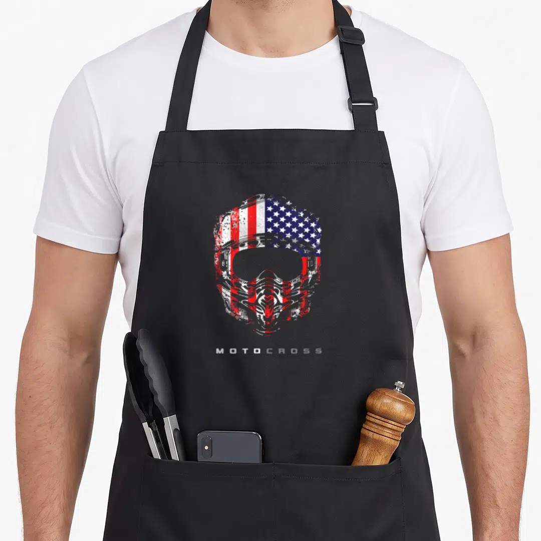 Dirt motocross bike apron - Distressed motocross helmet with red white blue flag pattern and MOTOCROSS text — shown on a black cotton canvas apron against a white background