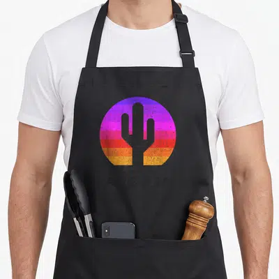 Summer cactus apron - Retro saguaro silhouette inside colorful striped circle with ARIZONA text below — shown on a black cotton canvas apron against a white background