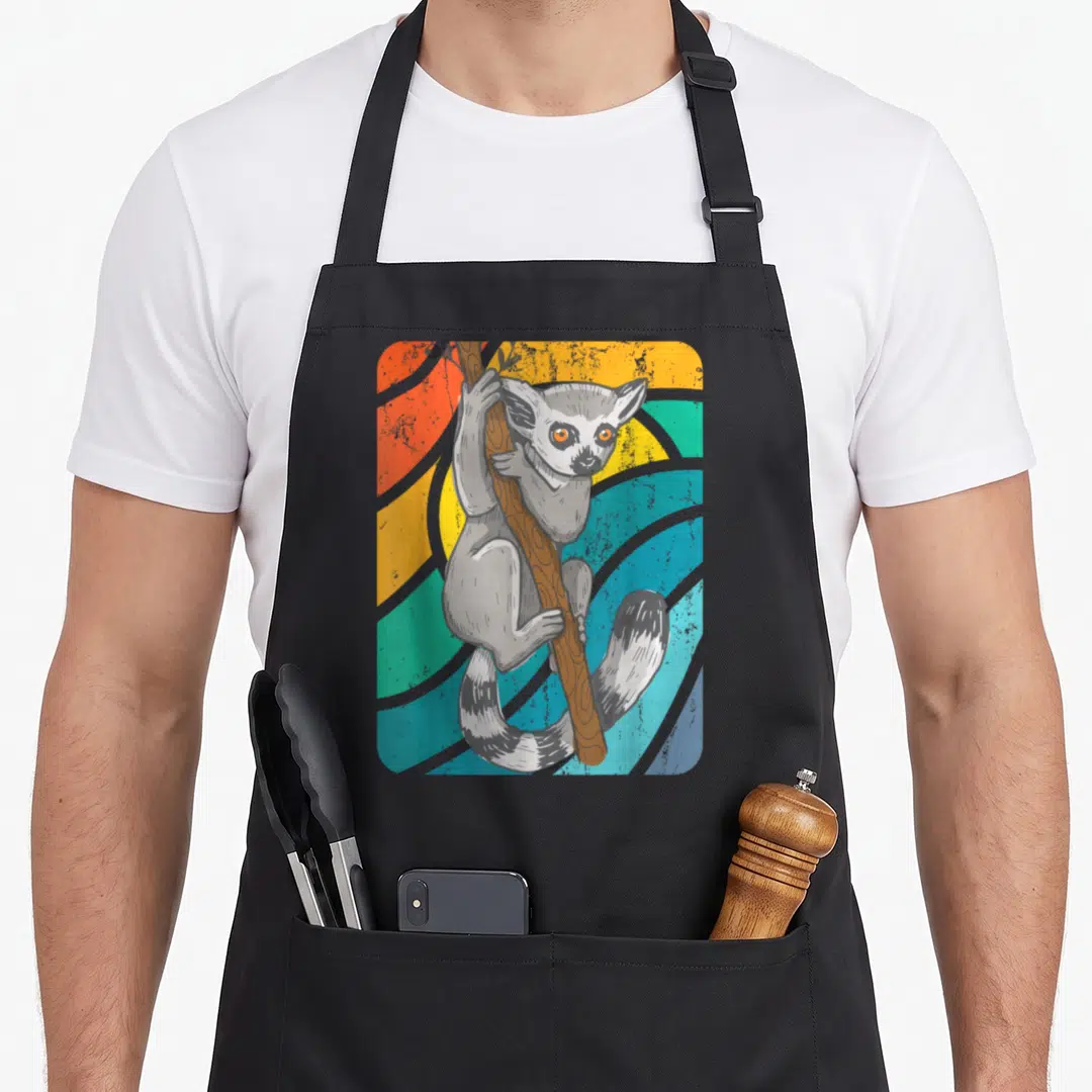 Tailed ring apron - grey lemur clinging to brown branch against orange teal yellow grey curved stripes retro art — shown on a black cotton canvas apron against a white background