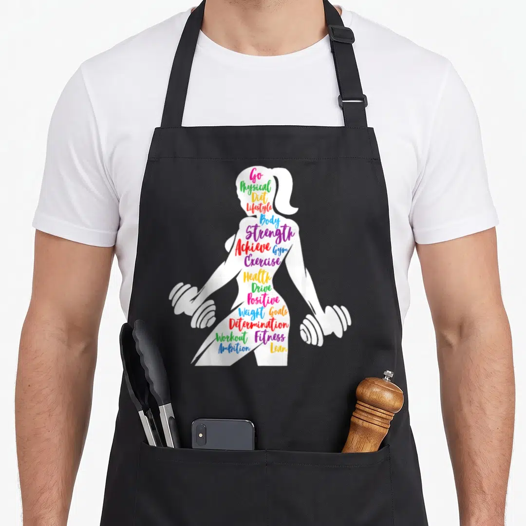 Gym burpees apron - Woman silhouette holding dumbbells filled with colorful words like Strength, Achieve, and Lean — shown on a black cotton canvas apron against a white background