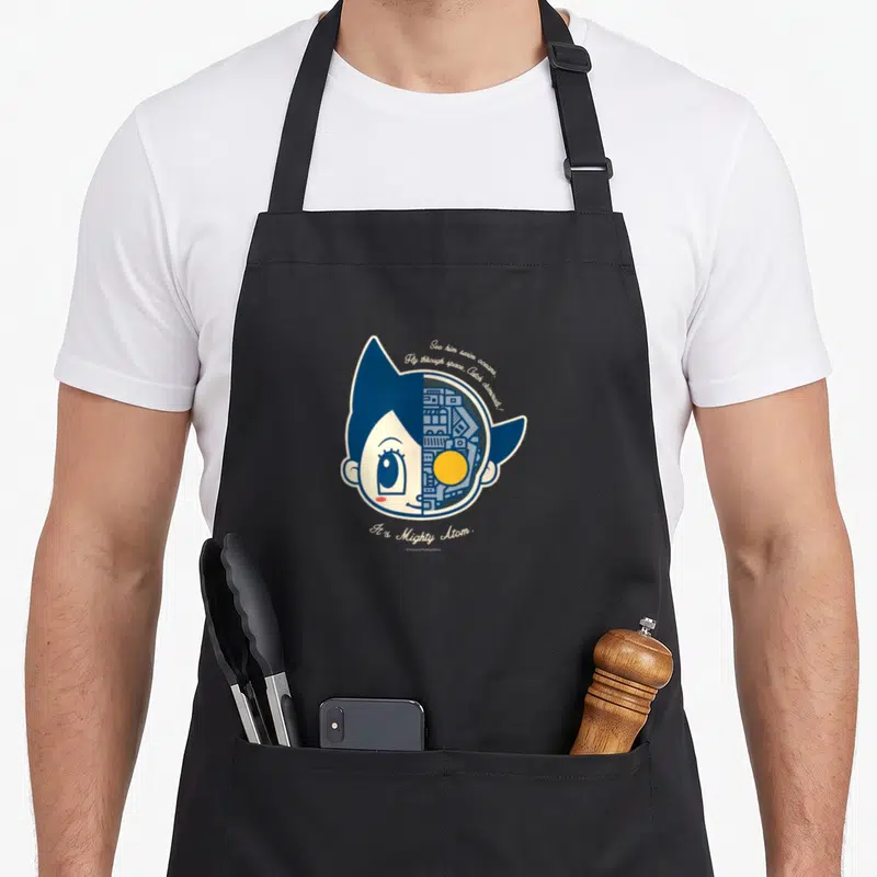 Astro astrophotography apron - Astro Boy head split showing robot interior with blue white yellow text See him swim — shown on a black cotton canvas apron against a white background