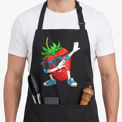 Dabbing strawberry apron - Cartoon red strawberry character wearing blue sunglasses, white gloves, and sneakers — shown on a black cotton canvas apron against a white background