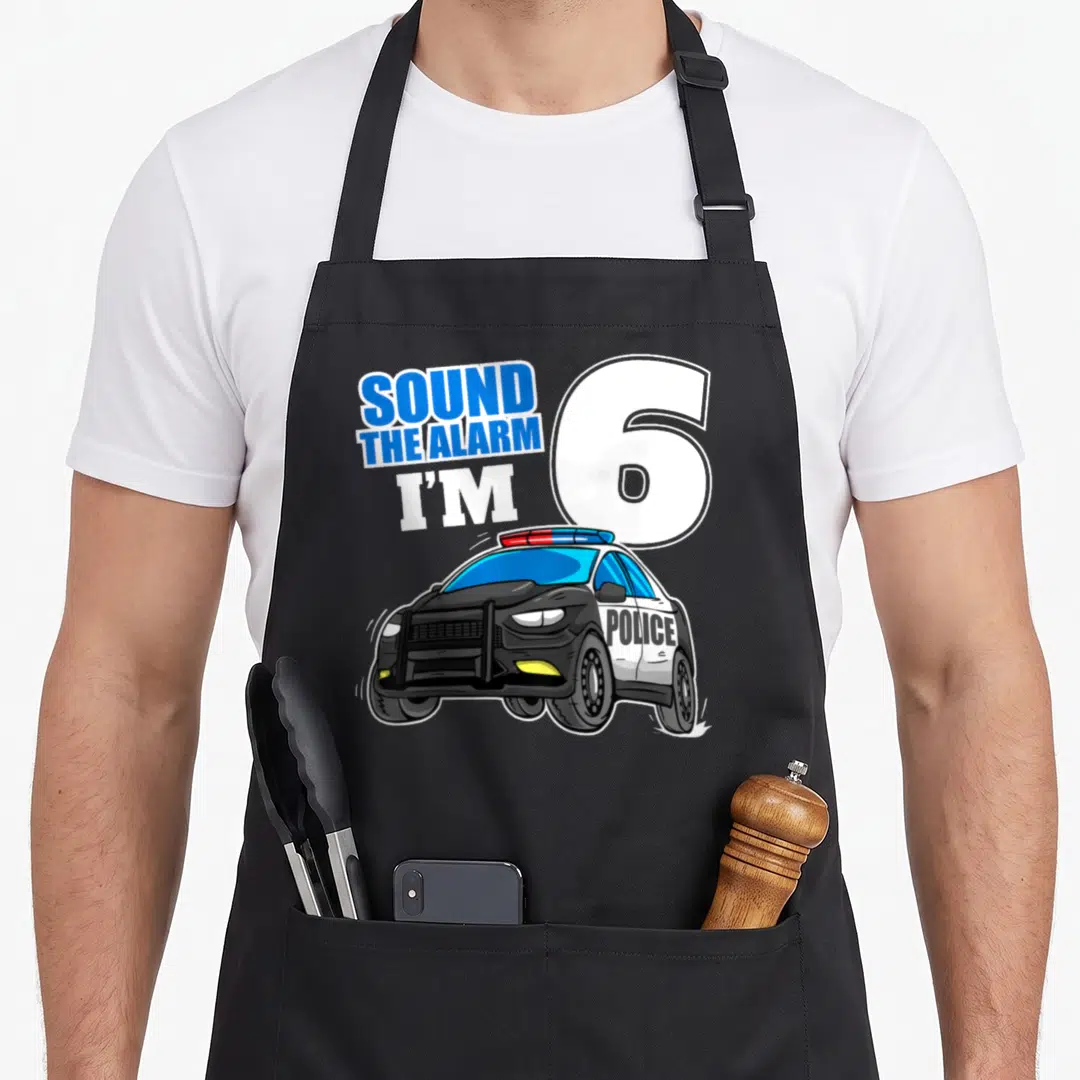6th car apron - SOUND THE ALARM I'M 6 text over blue white black and red police car with POLICE side lettering — shown on a black cotton canvas apron against a white background