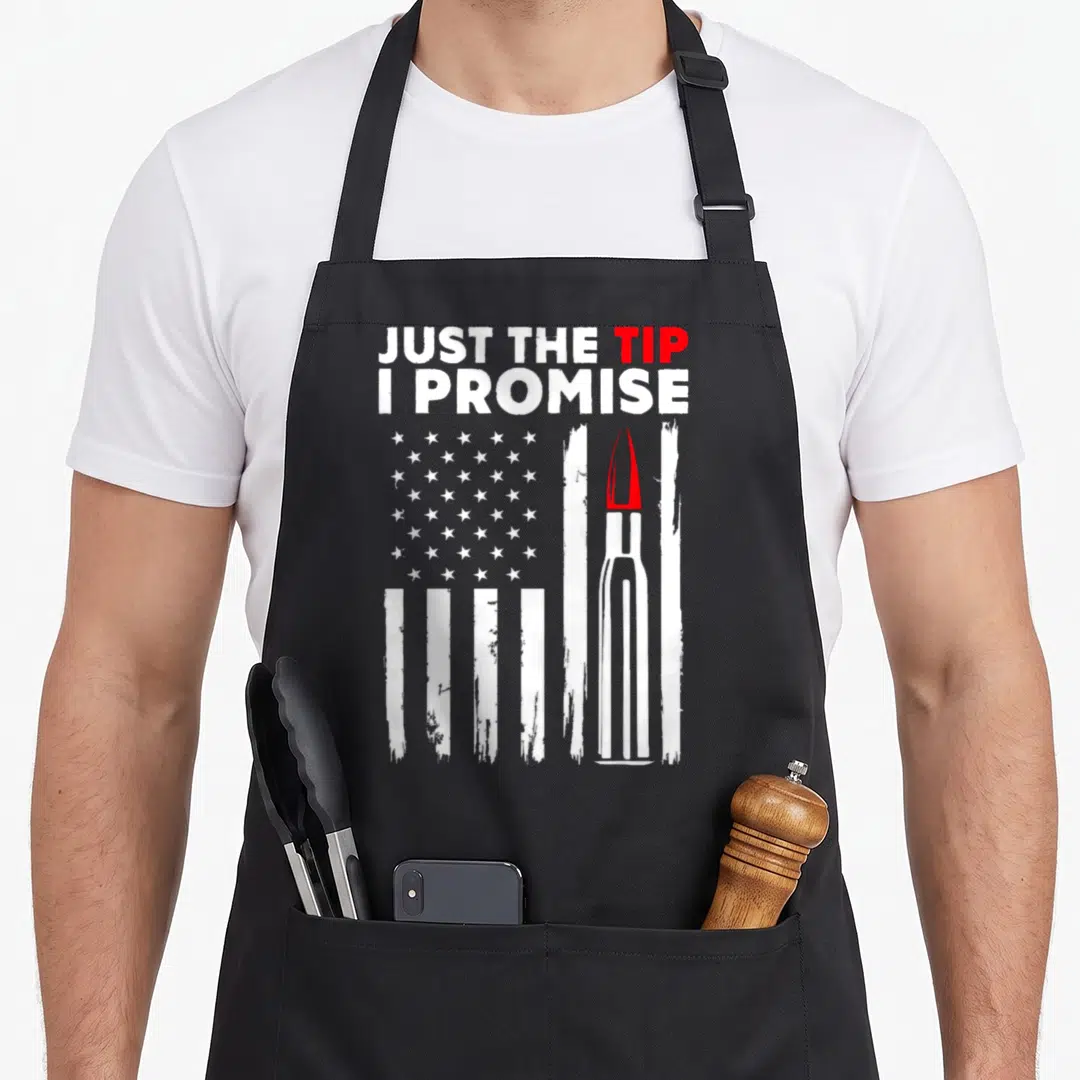 Tip bullet addict apron - Distressed US flag with a bullet replacing a stripe and text JUST THE TIP I PROMISE — shown on a black cotton canvas apron against a white background