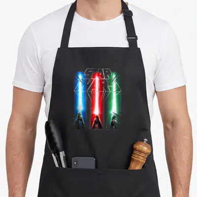 Epic war apron - Star Wars logo with three blue red and green lightsabers rising from hands — shown on a black cotton canvas apron against a white background