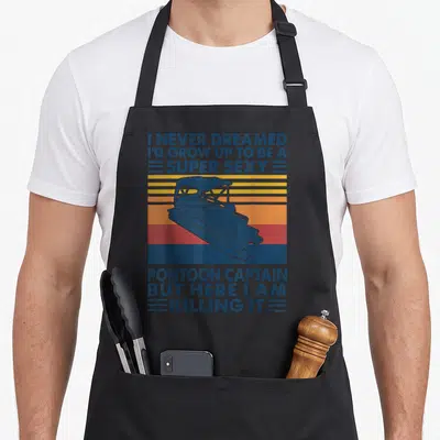 Grow pontoon apron - Retro blue pontoon boat over yellow orange red stripes with sarcastic captain quote text — shown on a black cotton canvas apron against a white background