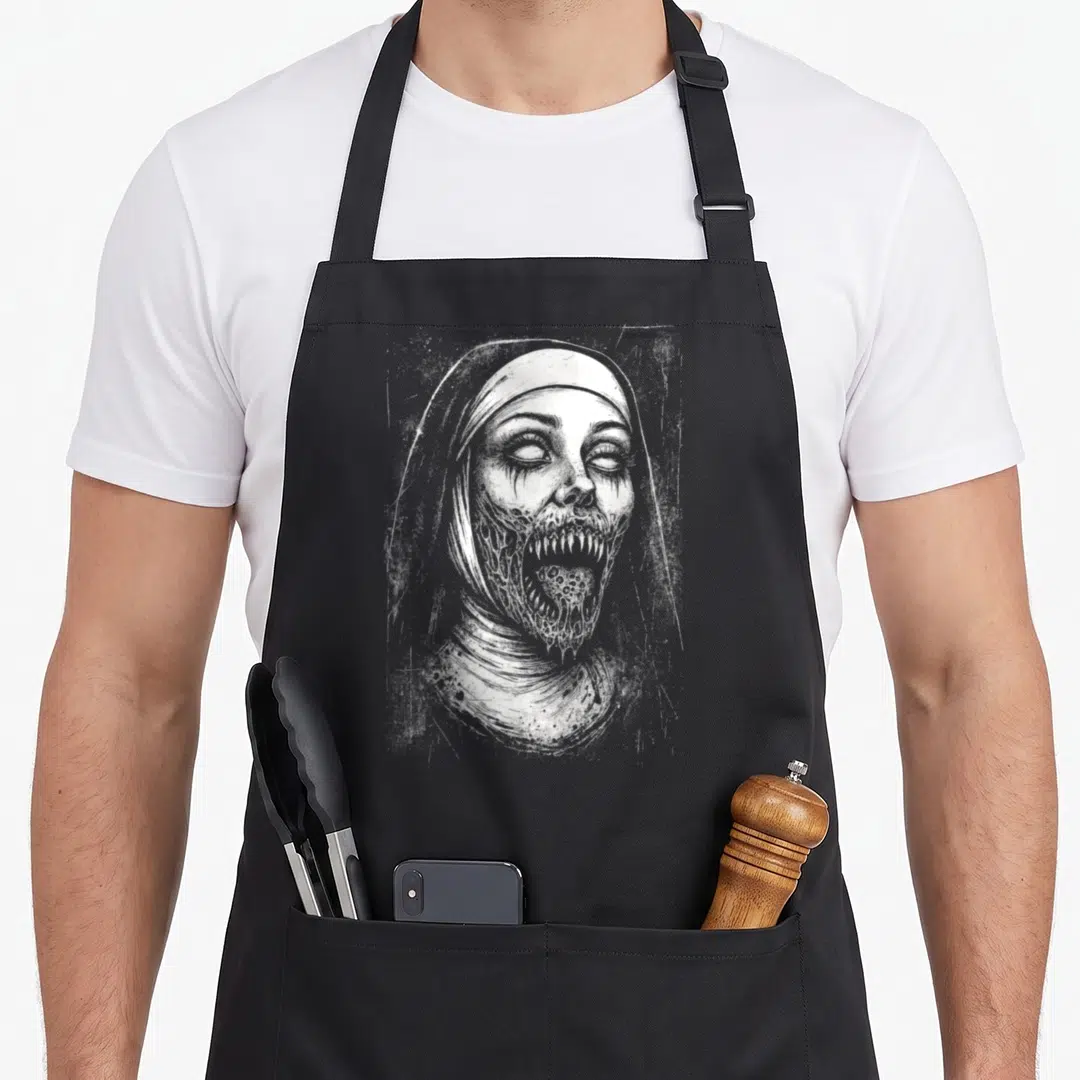 Nun goth apron - White line art of a zombie nun with decayed face and open mouth on black fabric — shown on a black cotton canvas apron against a white background