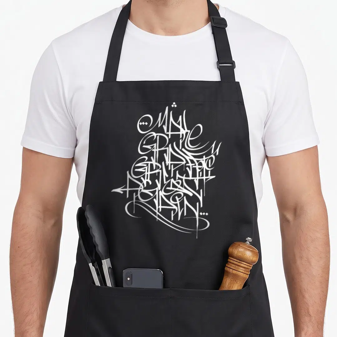 Graffiti tag apron - Abstract white calligraphic lines clustered in center, line art style, handstyle tag design — shown on a black cotton canvas apron against a white background