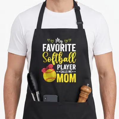 Softball call mom apron - Stacked text My Favorite Softball Player Calls Me Mom with yellow ball and red bow — shown on a black cotton canvas apron against a white background