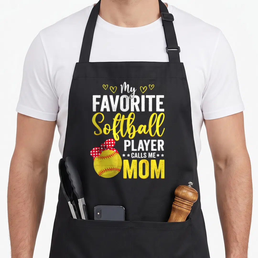 Softball call mom apron - Stacked text My Favorite Softball Player Calls Me Mom with yellow ball and red bow — shown on a black cotton canvas apron against a white background