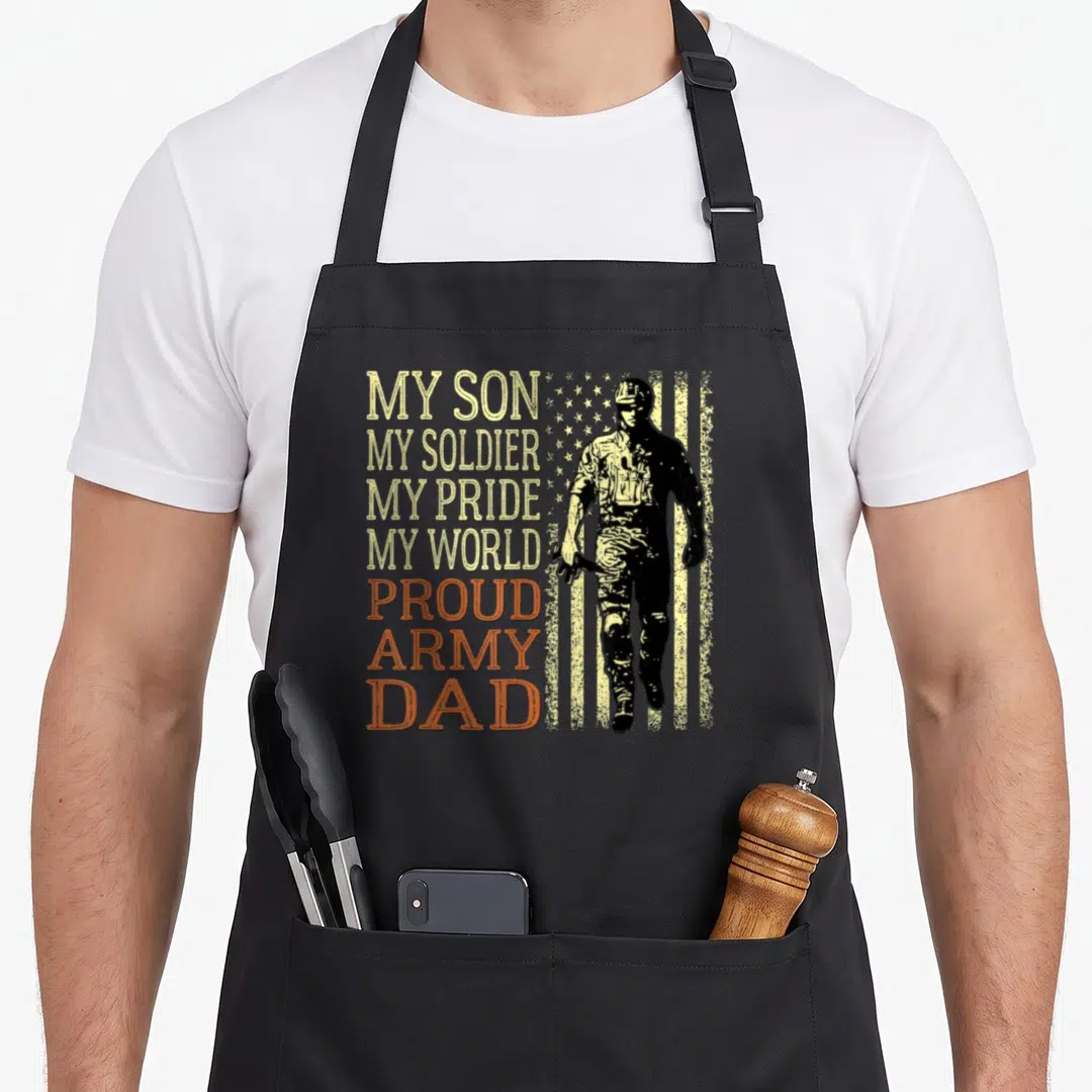 Soldier father son apron - My Son My Soldier My Pride My World text next to soldier silhouette on distressed flag — shown on a black cotton canvas apron against a white background