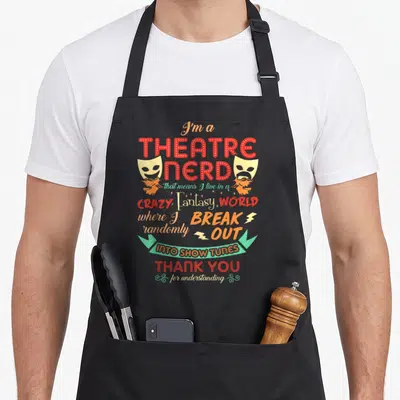 Theatre theater apron - Red and yellow typography reading I'm a Theatre Nerd with drama masks and teal ribbon around — shown on a black cotton canvas apron against a white background