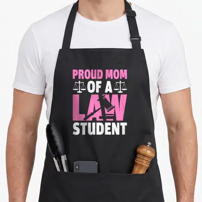Proud student aprons - PROUD MOM OF A LAW STUDENT text with scales and gavel in pink white grey — shown on a black cotton canvas apron against a white background
