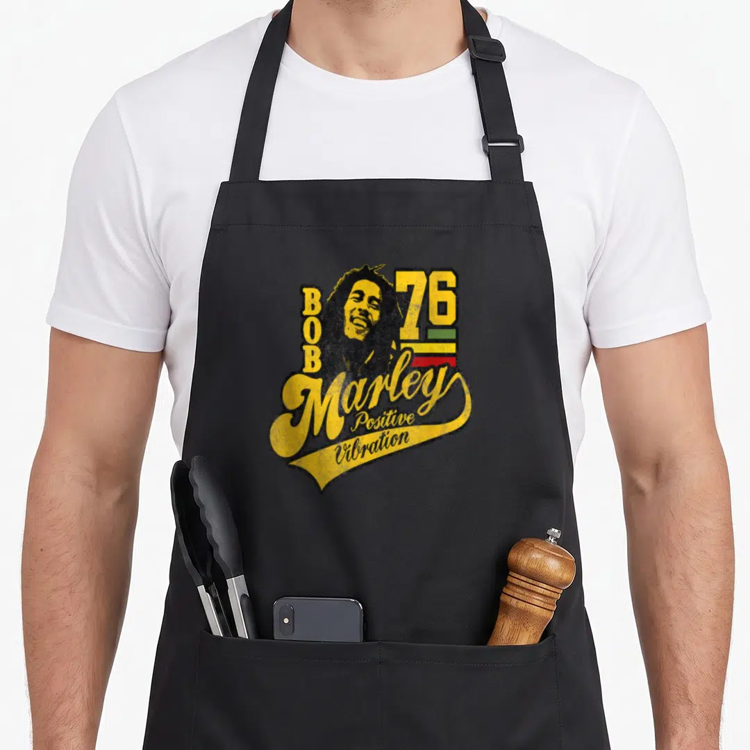 Bob soccer apron - Retro Bob Marley portrait with 76 and positive vibration script over colored stripes — shown on a black cotton canvas apron against a white background