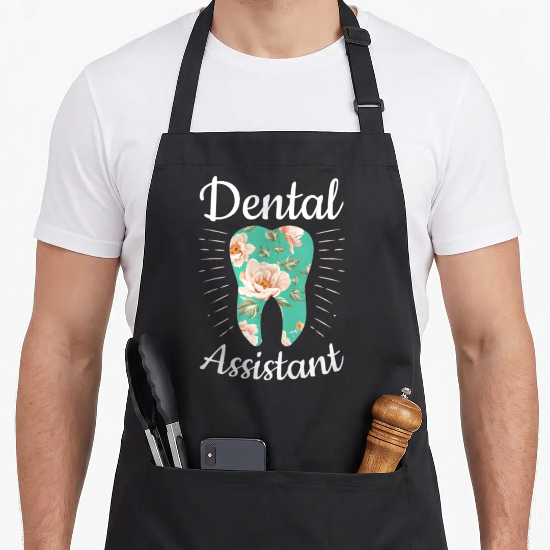 Dental floral apron - Floral tooth graphic with white Dental Assistant text on teal background — shown on a black cotton canvas apron against a white background