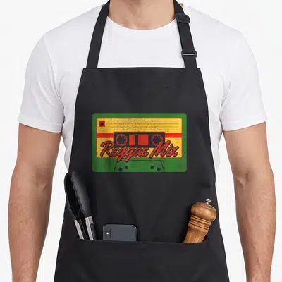 Mix reggaeton apron - Retro cassette tape in green yellow and red with Reggae Mix text and A side label — shown on a black cotton canvas apron against a white background
