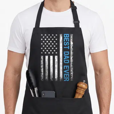 Vintage father american flag apron - Distressed USA flag with vertical blue BEST DAD EVER text on white stripe — shown on a black cotton canvas apron against a white background