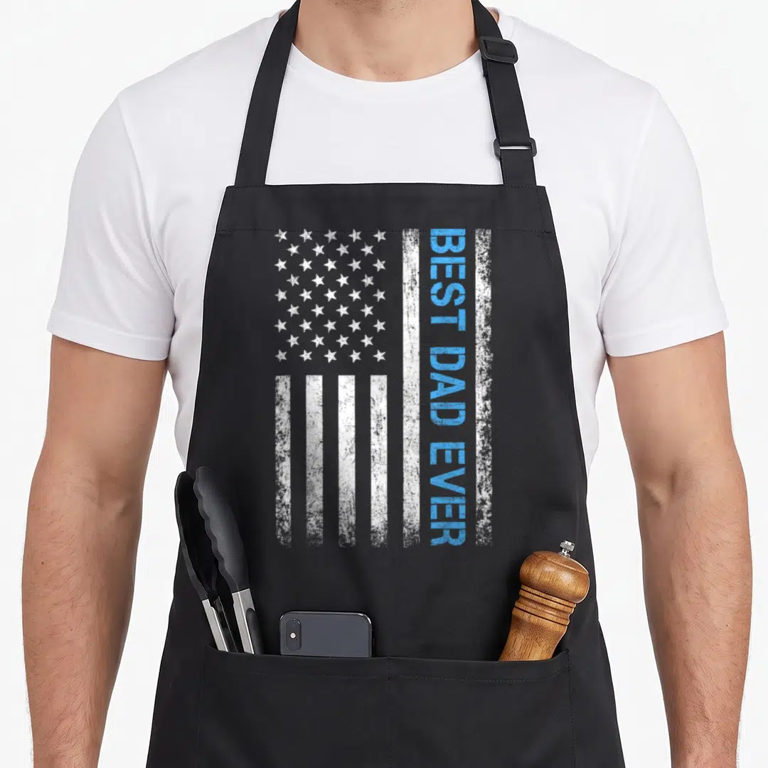 Vintage father american flag apron - Distressed USA flag with vertical blue BEST DAD EVER text on white stripe — shown on a black cotton canvas apron against a white background