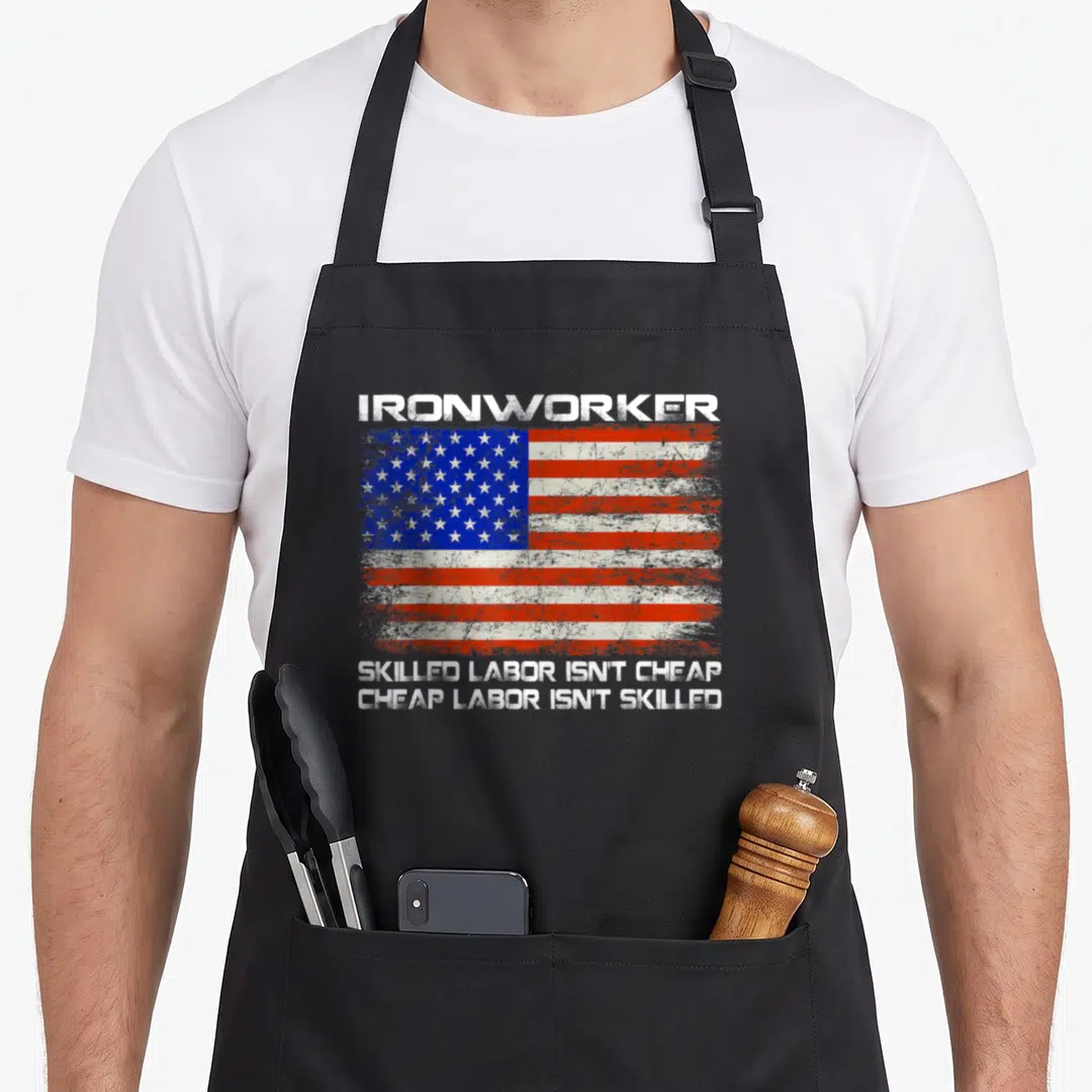 Ironworker american flag apron - Distressed USA flag with ironworker text and skilled labor quote on black fabric — shown on a black cotton canvas apron against a white background