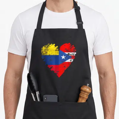 Colombia colombian boy apron - Distressed heart split vertically with yellow blue red bands and red white blue star — shown on a black cotton canvas apron against a white background