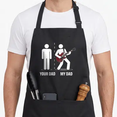 Father music dad apron - Two white stick figures separated by dashed line, one stands still, other plays maroon guitar — shown on a black cotton canvas apron against a white background