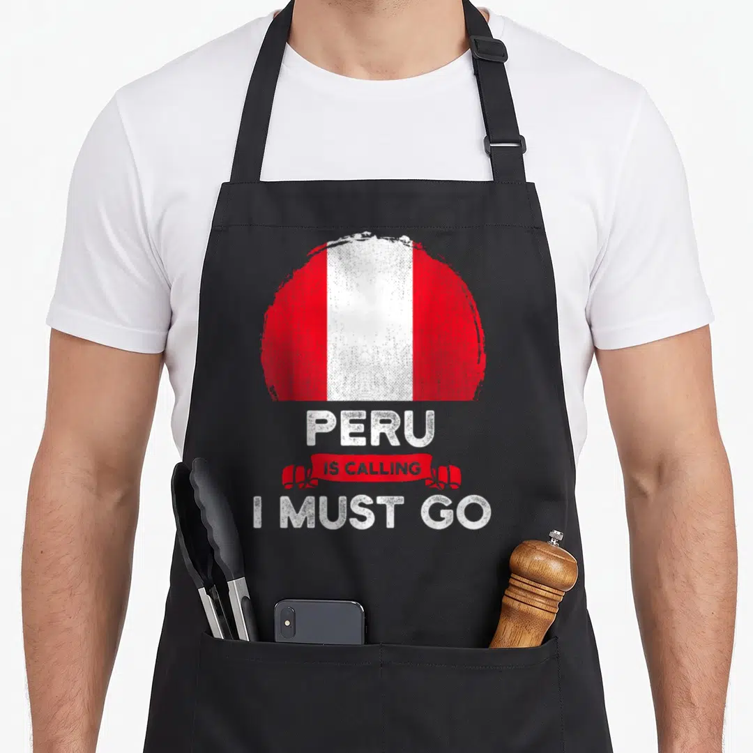 Must pride apron - Circular red white flag graphic above stacked text reading Peru Is Calling I Must Go — shown on a black cotton canvas apron against a white background