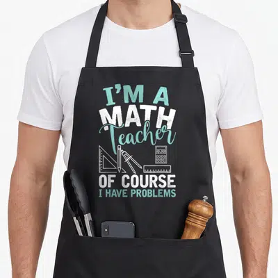 Cool math teacher apron - Stacked text I'M A MATH Teacher OF COURSE I HAVE PROBLEMS with ruler compass and calculator — shown on a black cotton canvas apron against a white background