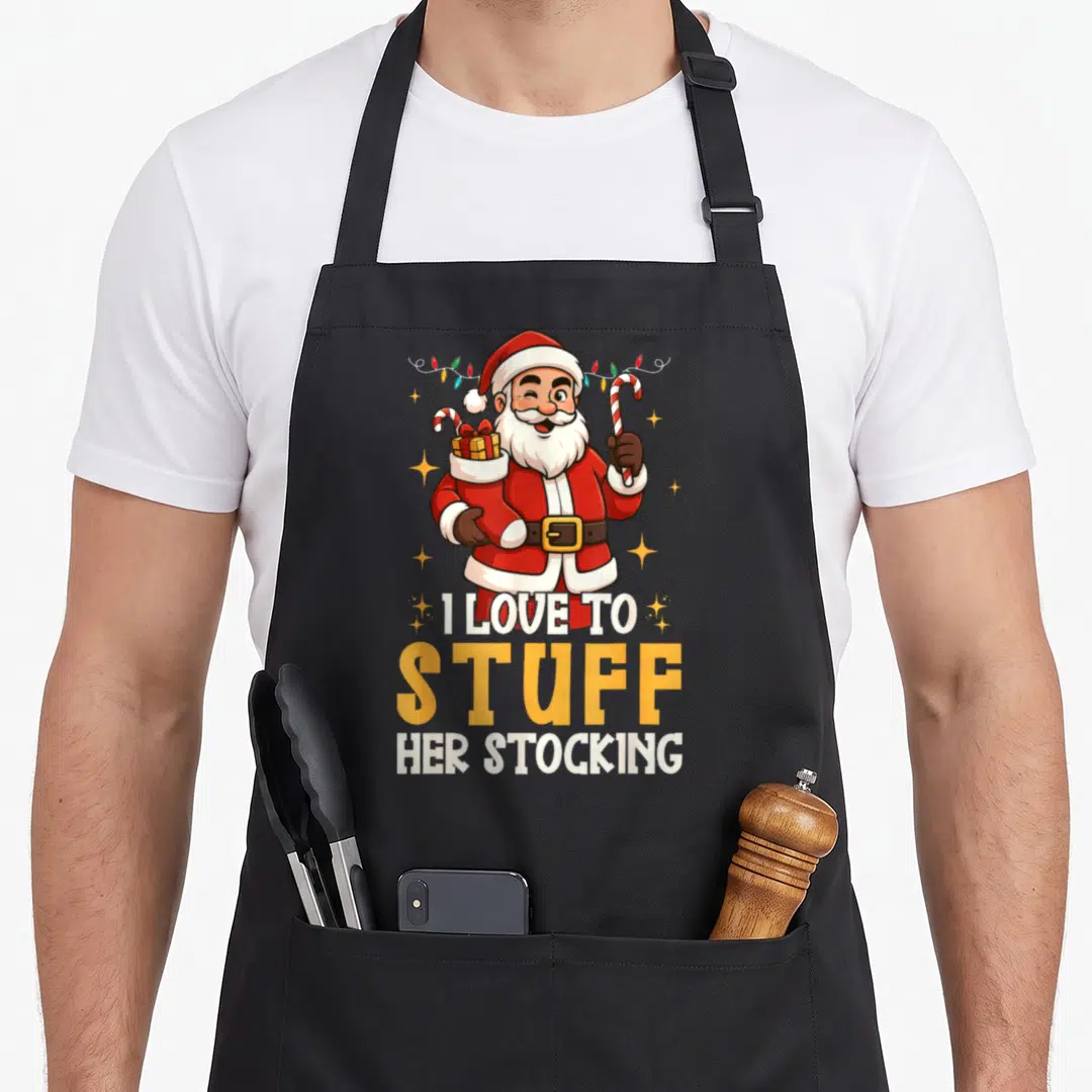 Couple womens christmas aprons - Cartoon Santa holding gifts and candy canes with text I Love To Stuff Her Stocking — shown on a black cotton canvas apron against a white background