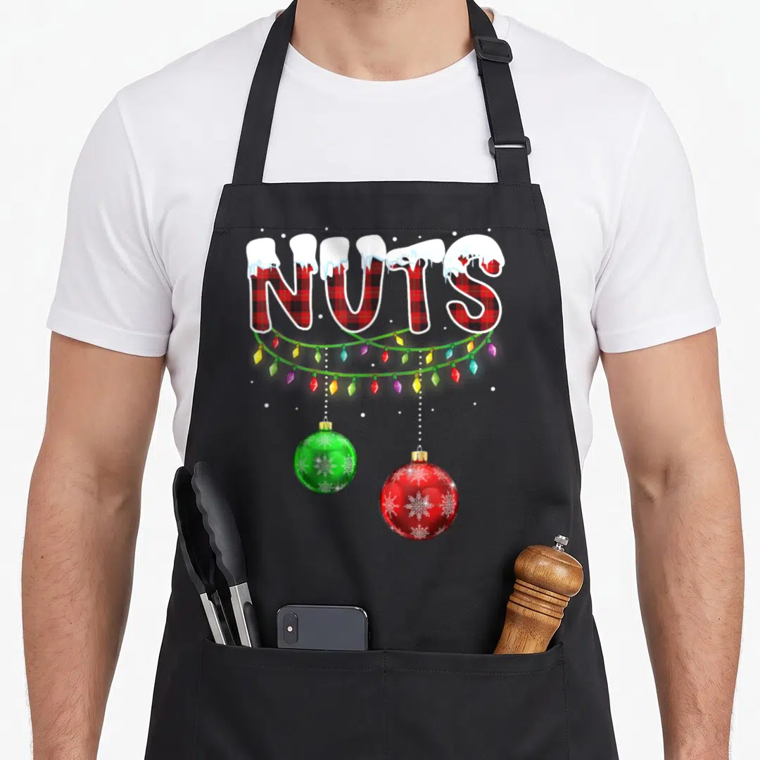 Cute chest couples christmas aprons - NUTS text in red plaid with snow, green lights, and two hanging red and green — shown on a black cotton canvas apron against a white background