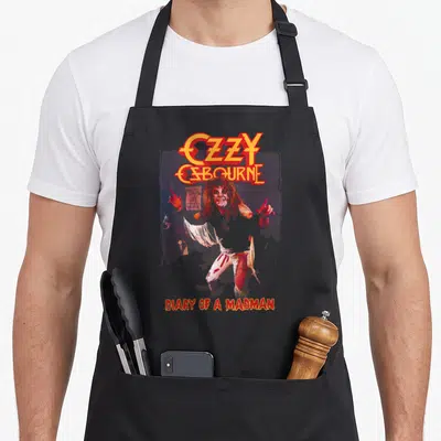 Diary ozzy osbourne apron - OZZY OSBOURNE logo in orange and red above a photo of the artist with text DIARY — shown on a black cotton canvas apron against a white background