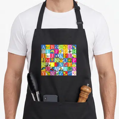 Funny z apron - Colorful alphabet grid with cartoon creatures and Dr Seuss signature — shown on a black cotton canvas apron against a white background