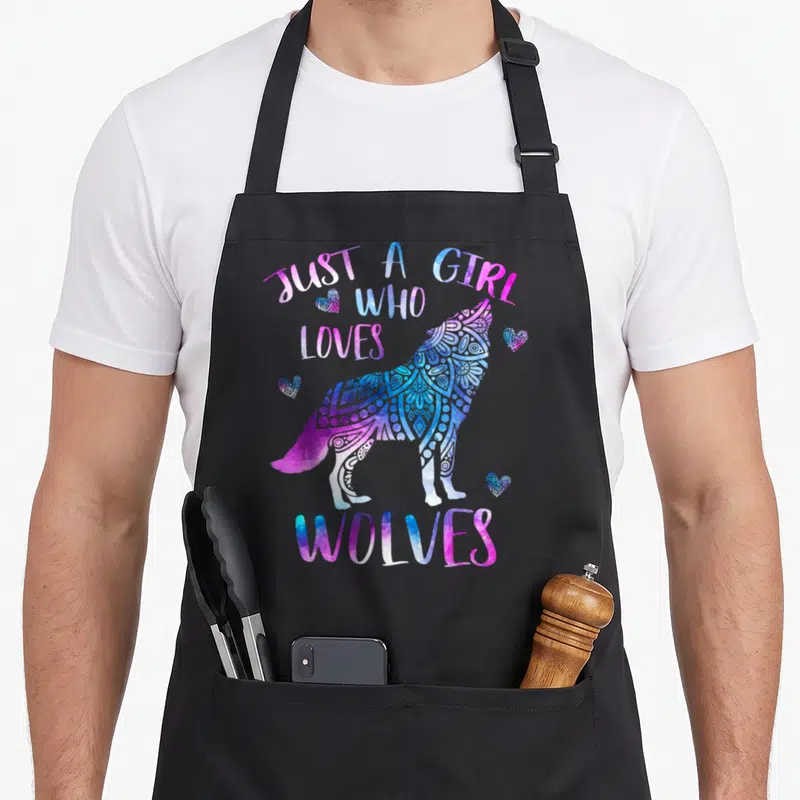 Ornament wolves apron - Watercolor wolf silhouette in blue, pink, purple, and white with four hearts and arched text — shown on a black cotton canvas apron against a white background