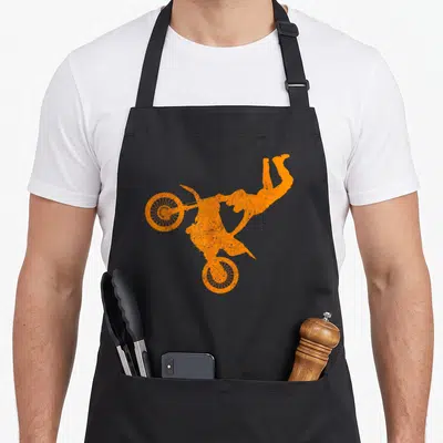 Freestyle bike apron - Orange silhouette of motocross rider and bike performing an aerial flip stunt — shown on a black cotton canvas apron against a white background