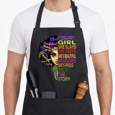 Magic african apron - Stylized woman portrait with Black Confident Melanin Educated Proud Strong text in yellow pink — shown on a black cotton canvas apron against a white background