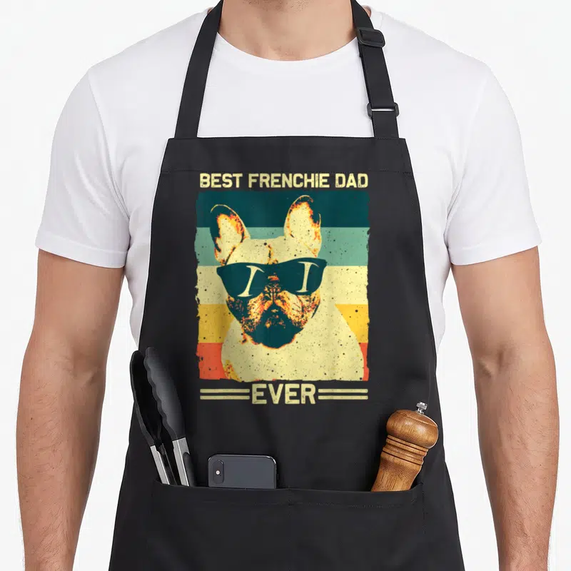 Father french bulldog apron - Retro French Bulldog with sunglasses on beige teal orange yellow striped background — shown on a black cotton canvas apron against a white background