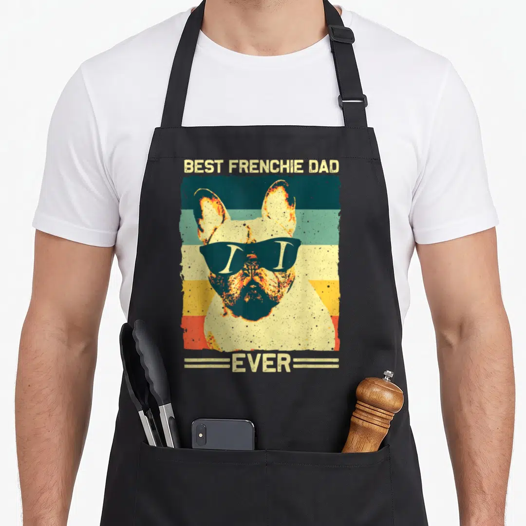 Father french bulldog apron - Retro French Bulldog with sunglasses on beige teal orange yellow striped background — shown on a black cotton canvas apron against a white background