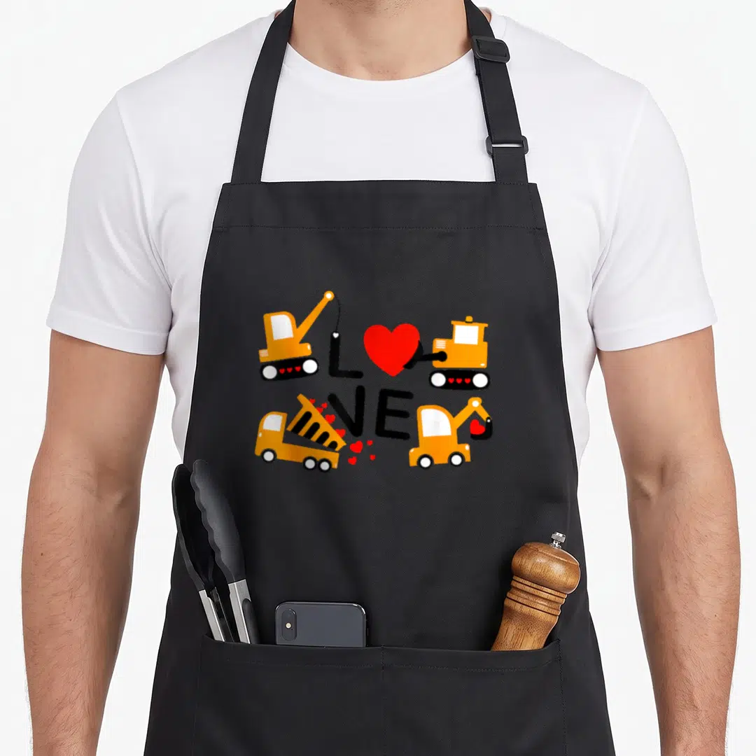 Construction valentine's day apron - Orange excavators and dump truck forming the word love with scattered red hearts — shown on a black cotton canvas apron against a white background