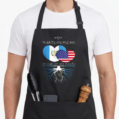 Guatemala country apron - Two overlapping hearts in blue white and red with roots and Guatemerican text — shown on a black cotton canvas apron against a white background