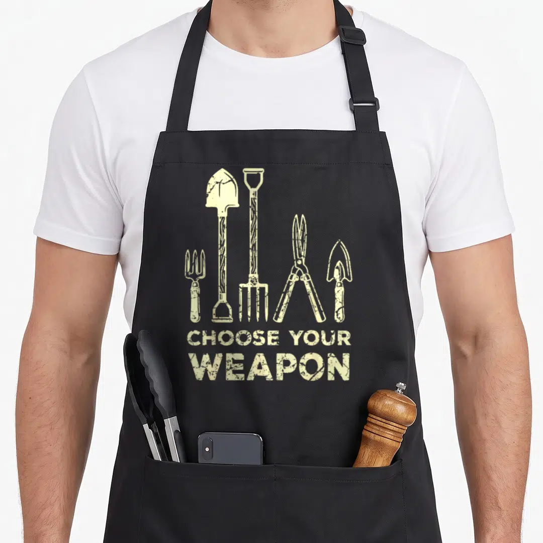 Flower gardener apron - Beige distressed illustrations of five gardening tools above stacked text reading CHOOSE YOUR — shown on a black cotton canvas apron against a white background