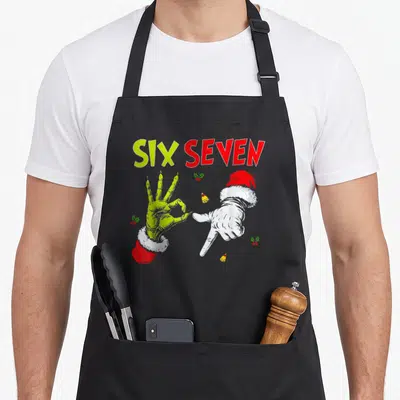 Seven christmas santa apron - SIX SEVEN text above lime and white hands in Santa hats with holly and bells — shown on a black cotton canvas apron against a white background