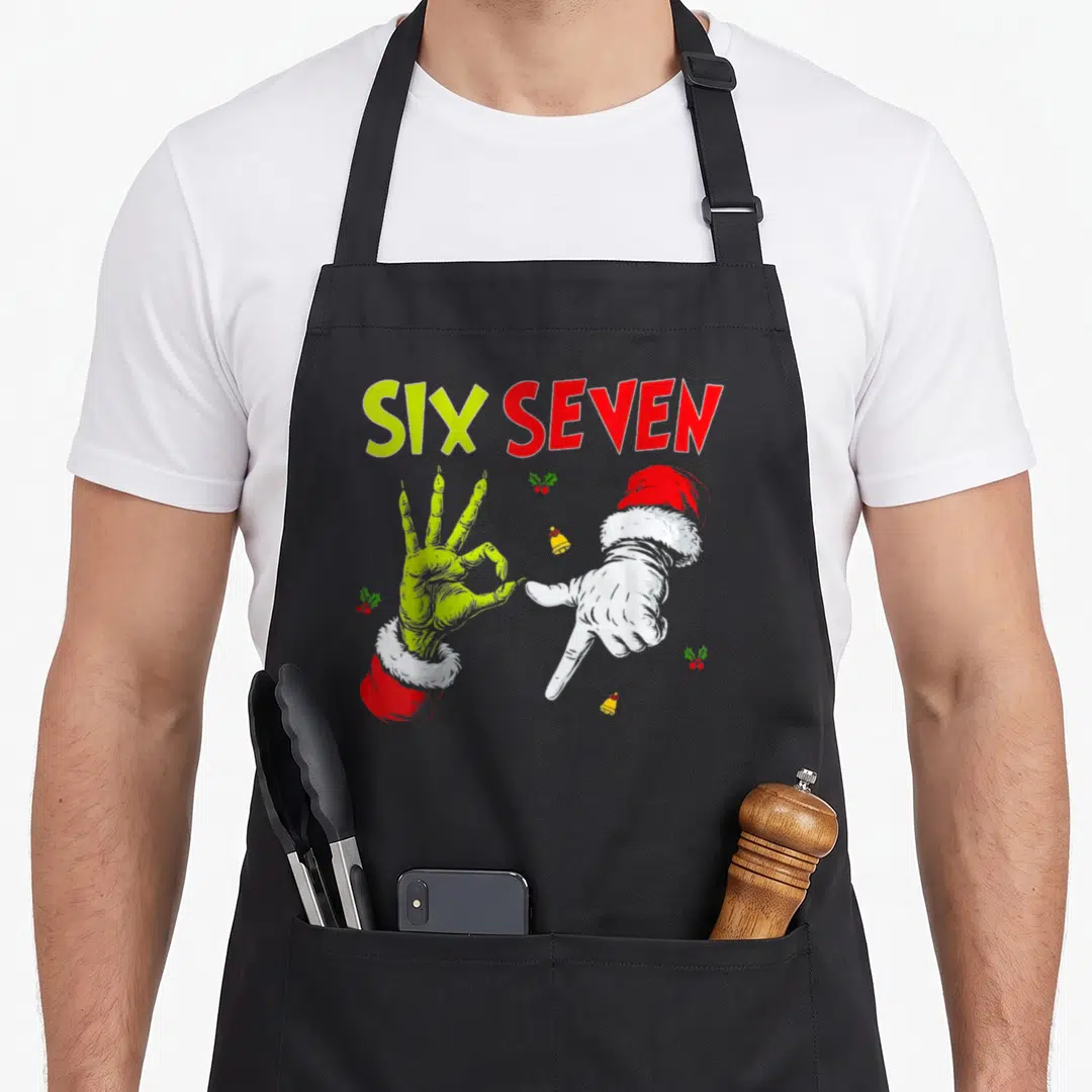Seven christmas santa apron - SIX SEVEN text above lime and white hands in Santa hats with holly and bells — shown on a black cotton canvas apron against a white background