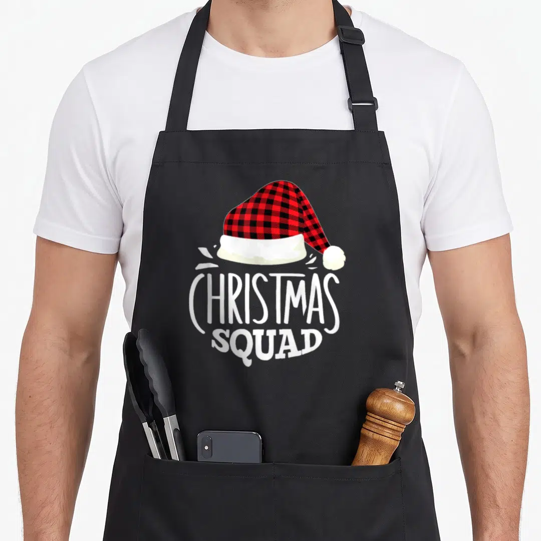 Squad personalized family aprons - Red and black plaid Santa hat above white CHRISTMAS SQUAD text — shown on a black cotton canvas apron against a white background
