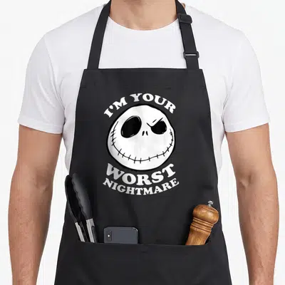 Worst jack apron - White cartoon skull with stitched smile and I'M YOUR WORST NIGHTMARE text in black and white — shown on a black cotton canvas apron against a white background