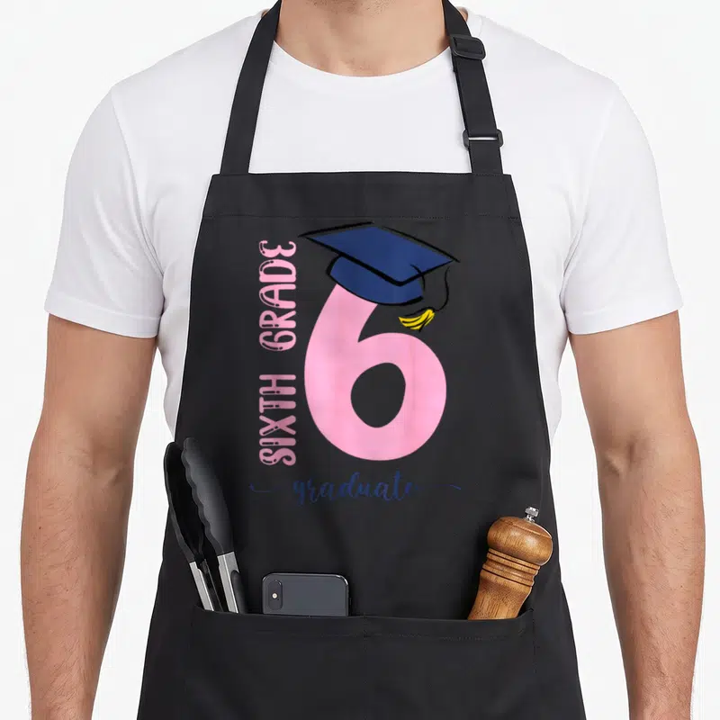 6th student aprons - Pink number 6 with navy graduation cap and yellow tassel celebrating sixth grade — shown on a black cotton canvas apron against a white background