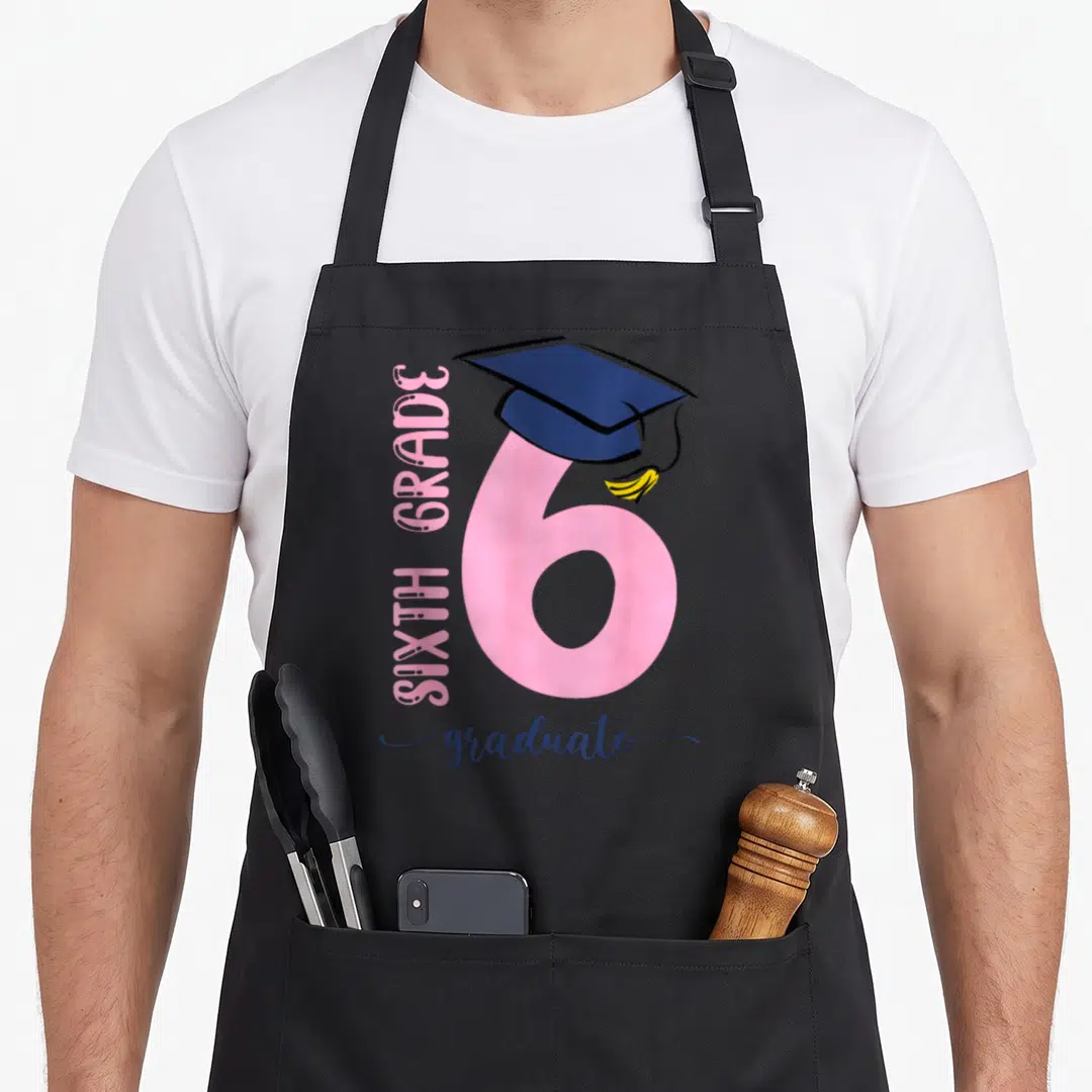 6th student aprons - Pink number 6 with navy graduation cap and yellow tassel celebrating sixth grade — shown on a black cotton canvas apron against a white background