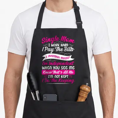 Hard single mother's day aprons - Pink and white typography reading Single Mom I Work Hard with two hearts flanking I'm — shown on a black cotton canvas apron against a white background