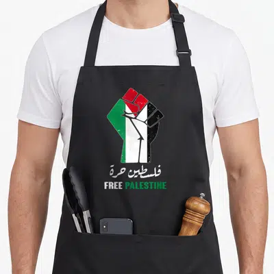 Matter palestinian apron - Raised fist in red black white and green flag colors with free palestine text below — shown on a black cotton canvas apron against a white background