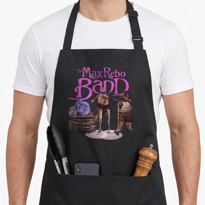 Max 70s apron - Three aliens and instrument below pink arched text The Max Rebo Band — shown on a black cotton canvas apron against a white background