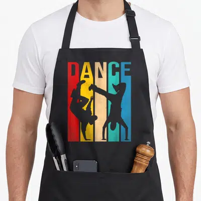 Breakdancing dancer apron - DANCE text above five red yellow teal blue grey vertical stripes with two grey dancer — shown on a black cotton canvas apron against a white background